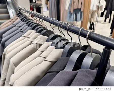 New stylish classic cut jackets in pastel shades are hanging on hangers in a clothing store 134227381