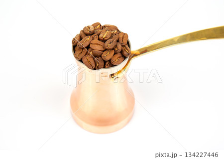 Authentic copper coffee pot with a brass handle next to a spread of coffee beans 134227446