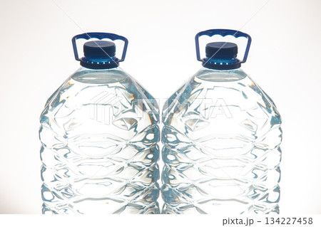 A pair of clear plastic water bottles with blue lids, featuring a wavy texture A pair of clear plastic water bottles with blue lids, featuring a wavy texture 134227458