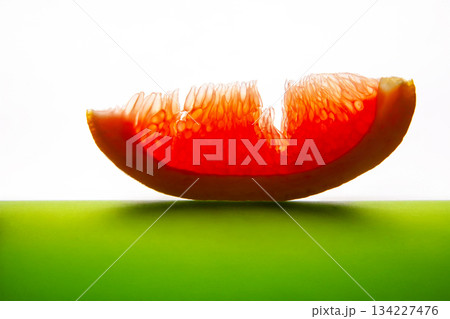 A vibrant half grapefruit with juicy red flesh, sliced and placed on a reflective green A vibrant half grapefruit with juicy red flesh, sliced and placed on a reflective green 134227476
