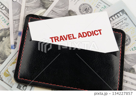 A stylish black wallet lies on a pile of cash, revealing a card that boldly declares travel addict, symbolizing the joy of exploration and adventure A stylish black wallet lies on a pile of cash, revealing a card that boldly declares travel addict, symbolizing the joy of exploration and adventure 134227857