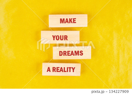Bright yellow backdrop features wooden blocks arranged to convey an uplifting message about making dreams a reality. Perfect for motivating individuals to chase their aspirations Bright yellow backdrop features wooden blocks arranged to convey an uplifting message about making dreams a reality. Perfect for motivating individuals to chase their aspirations 134227909