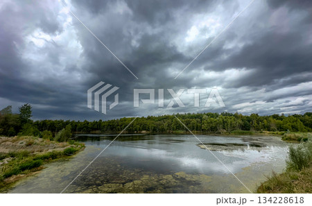 Cloudy sky with rugged shoreline and distant tree silhouette Cloudy sky with rugged shoreline and distant tree silhouette 134228618
