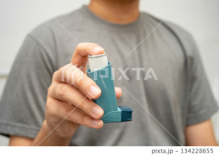 Asthma and chronic obstructive pulmonary disease COPD, Asian young man using metered dose inhaler MDI. 134228655