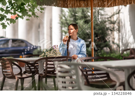 Woman Icecream Daisies, daytime: A woman eats icecream, by flowers at cafe in daylight outdoors. 134228846