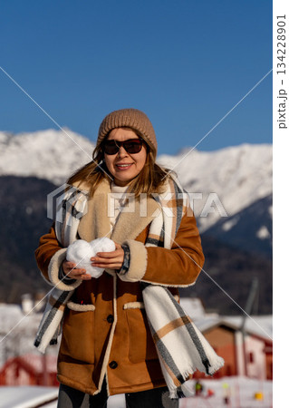 Snowball Mountains Winter: Woman playfully holds snowball, enjoying sunny winter day in mountainous region. 134228901