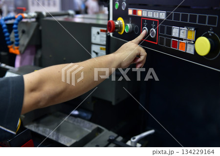 Machine operator hand turns on control panel of industrial machine. technician push button on control panel Machine operator hand turns on control panel of industrial machine. technician push button on control panel 134229164