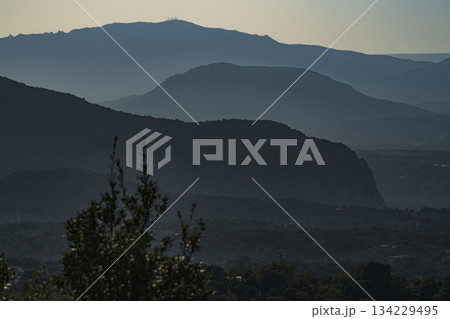 foggy mysterious bluish mountains in the distance. Layers of mountains in Sardinia in Italy at the sunset. 134229495