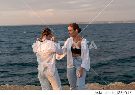 Couple, Beach, Sunset: Two women pose near the ocean at sunset. Couple, Beach, Sunset: Two women pose near the ocean at sunset. 134229512