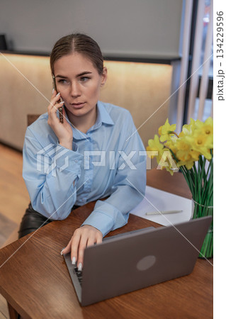 Businesswoman phone working attentive professional talking discussing communication laptop office Businesswoman phone working attentive professional talking discussing communication laptop office 134229596