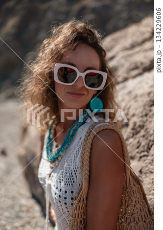 Woman, curly hair, sunglasses in white crochet top with bohemian style at a sunny outdoor location Woman, curly hair, sunglasses in white crochet top with bohemian style at a sunny outdoor location 134229606