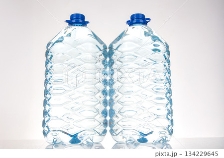 Two plastic water bottles with blue lids and a unique wavy design Two plastic water bottles with blue lids and a unique wavy design 134229645