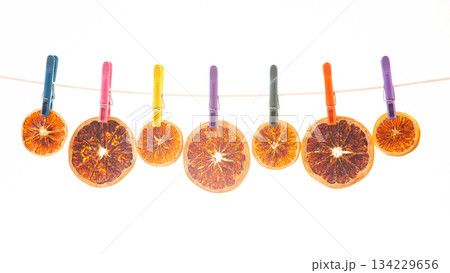 dried pieces of different citrus fruits hang on colored clothespins 134229656