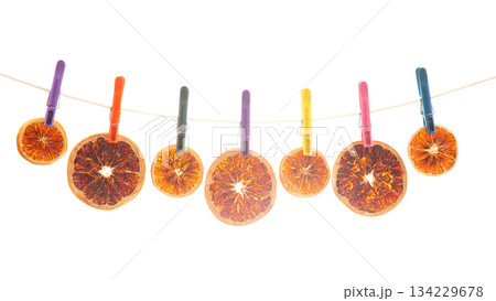 dried pieces of different citrus fruits hang on colored clothespins 134229678