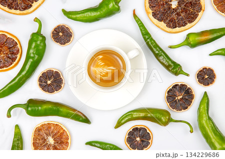 Top-down view of a frothy cappuccino in a white cup, encircled by dried citrus slices  134229686