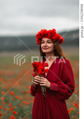 Woman poppies field emotional portrait in blooming meadow with moody cloudy sky Woman poppies field emotional portrait in blooming meadow with moody cloudy sky 134229698