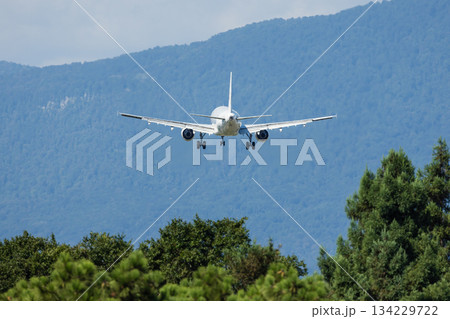 Passenger airplane landing with landing gear against the backdrop of mountains Passenger airplane landing with landing gear against the backdrop of mountains 134229722