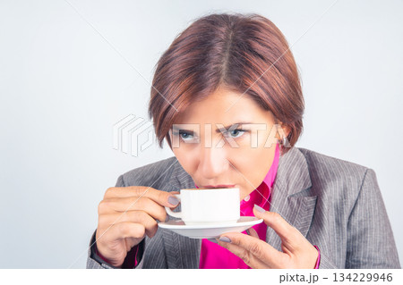 Business woman drinks coffee from a white cup close-up Business woman drinks coffee from a white cup close-up 134229946