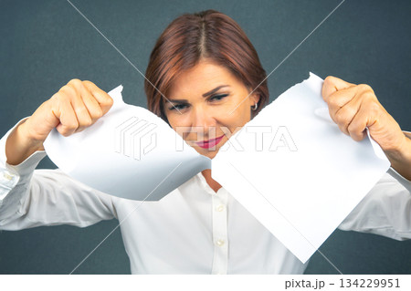 Beautiful business woman tearing white paper in half Beautiful business woman tearing white paper in half 134229951