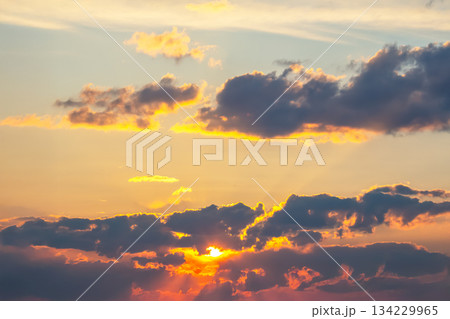 Dynamic sky with towering dark clouds and brilliant sunlight rays cutting through 134229965