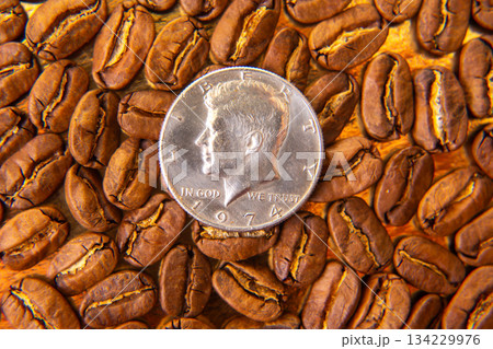 Roasted coffee beans with a dime for scale on a golden backdrop Roasted coffee beans with a dime for scale on a golden backdrop 134229976