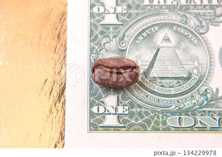 Detailed shot of a cracked coffee bean placed on a one-dollar bill, Detailed shot of a cracked coffee bean placed on a one-dollar bill, 134229978