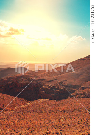 Mountainous desert with colorful cloudy sky. Judean desert in Israel at sunset. Vertical banner 134231253