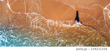 Seascape from above. A woman walks on the beach in summer. Travel happy holiday and summertime concept. Top view. Horizontal banner 134231338