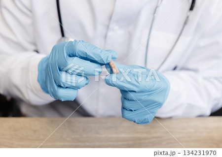 An otolaryngologist holds a hearing aid in his hands. The doctor consults the patient An otolaryngologist holds a hearing aid in his hands. The doctor consults the patient 134231970