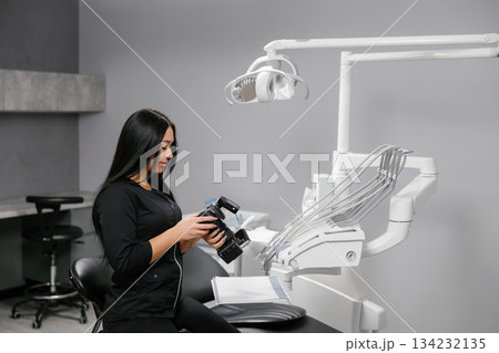 Young woman holding camera in modern dental clinic 134232135