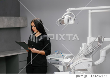 Woman dentist updating patients medical records Woman dentist updating patients medical records 134232137