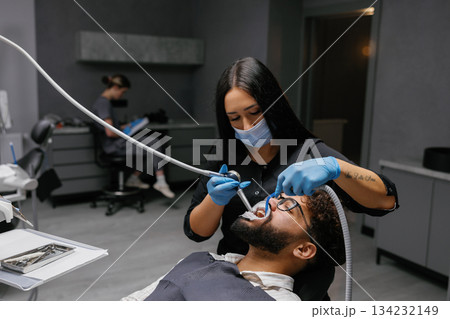 Dentist performing dental checkup on male patient Dentist performing dental checkup on male patient 134232149