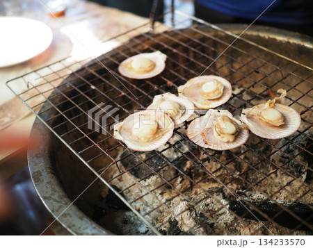 Grilled scallop shell seafood charcoal barbecue street food market fire smoke savory flavor 134233570