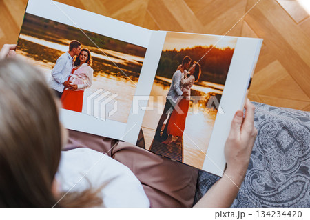 woman is holding and flipping through a photo book with a pregnancy photo shoot woman is holding and flipping through a photo book with a pregnancy photo shoot 134234420