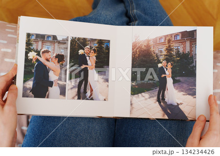 Female hands flipping through a photo book with wedding photos 134234426