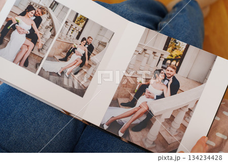 Female hands flipping through a photo book with wedding photos 134234428