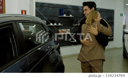 Couple inspecting a new car exterior with a smiling male car dealer Couple inspecting a new car exterior with a smiling male car dealer 134234764