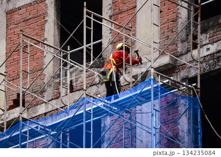Construction Worker on Scaffolding at Urban Building Site Construction Worker on Scaffolding at Urban Building Site 134235084
