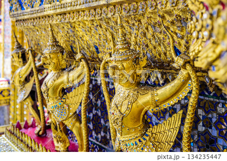 Three golden statues of winged creatures are displayed on a wall 134235447