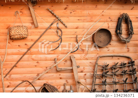 Rustic display of traditional farming tools on wooden wall in countryside 134236371