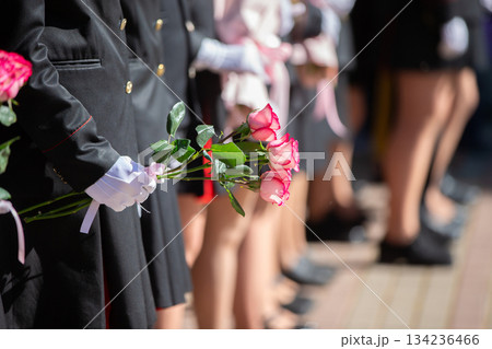 Hands in white gloves of an unrecognizable man in uniform holding a bouquet of roses. Hands in white gloves of an unrecognizable man in uniform holding a bouquet of roses. 134236466