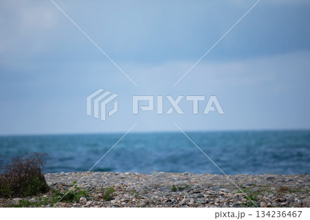 Beach with a small area of ??pebbles and the sea. The sky is cloudy and the water is blue. Beach with a small area of ??pebbles and the sea. The sky is cloudy and the water is blue. 134236467