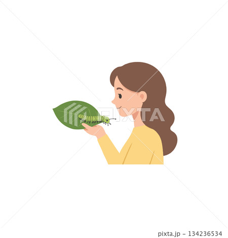 Young woman carefully examining a vibrant green caterpillar resting on a fresh leaf in daylight 134236534