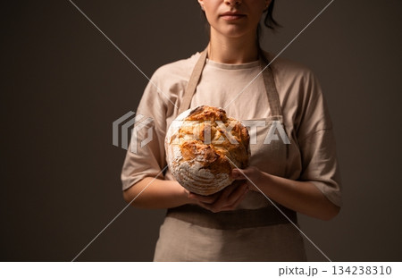 Artisan baker presenting rustic handmade bread loaf, showcasing traditional craftsmanship and natural quality 134238310