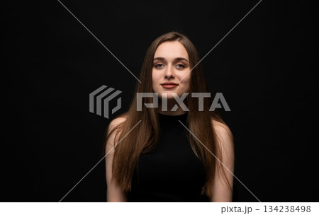Young woman on black background with calm confident expression and natural look Young woman on black background with calm confident expression and natural look 134238498