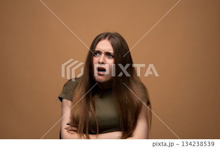 Confused shocked young woman reacting with open mouth, expressive emotional portrait on warm studio backdrop 134238539