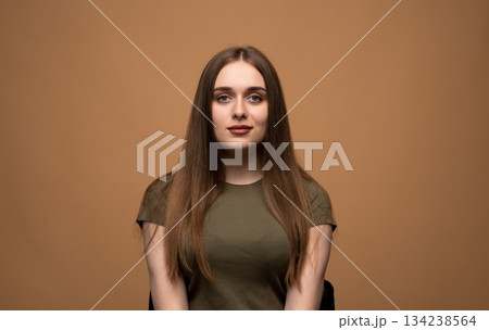 Calm young woman neutral portrait on beige background, natural beauty expression in studio setting 134238564