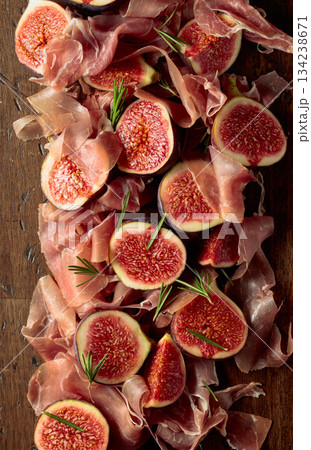 Prosciutto with rosemary and fig fruit on an old wooden table. Prosciutto with rosemary and fig fruit on an old wooden table. 134238671