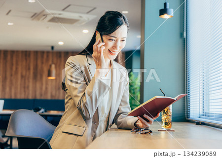オフィスで資料を見ながら電話をするビジネスウーマン 134239089