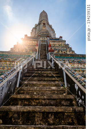 Detailed view of the ornate towers of Wat Arun in Bangkok, Thailand, showcasing rich ceramic floral patterns, sculpted figures, and intricate decorations under bright daylight. Detailed view of the ornate towers of Wat Arun in Bangkok, Thailand, showcasing rich ceramic floral patterns, sculpted figures, and intricate decorations under bright daylight. 134239131